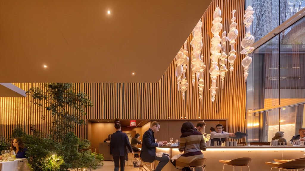Soaring dining room interior featuring live indoor trees and blown-glass chandeliers at Le Pavillon.