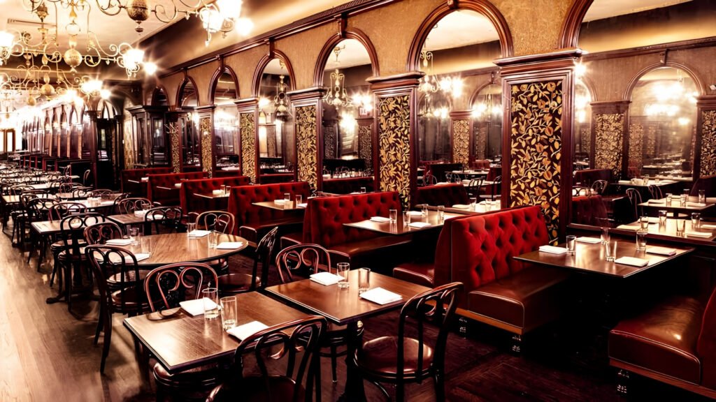 Restored Gilded-Age dining room with brass chandeliers and cherry wood trim at Gage & Tollner.